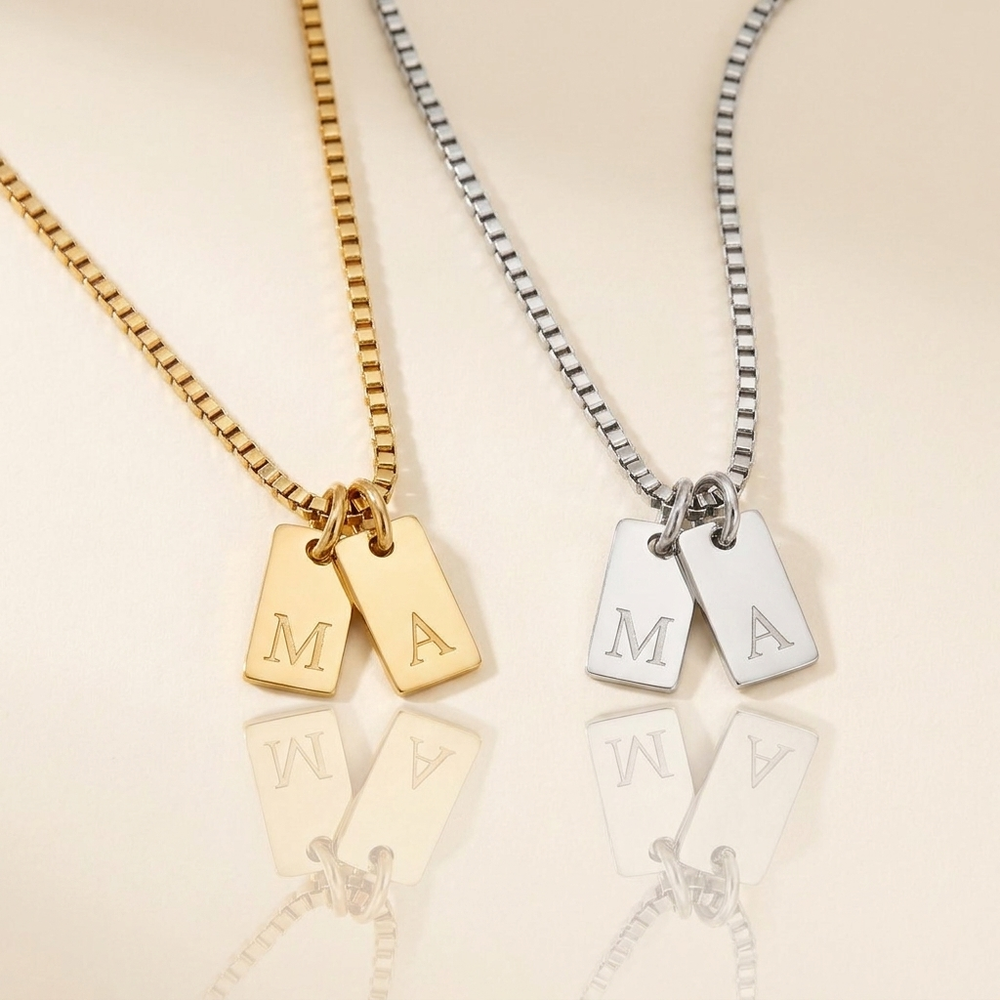 Collier Plaques Initiales tenu à la main